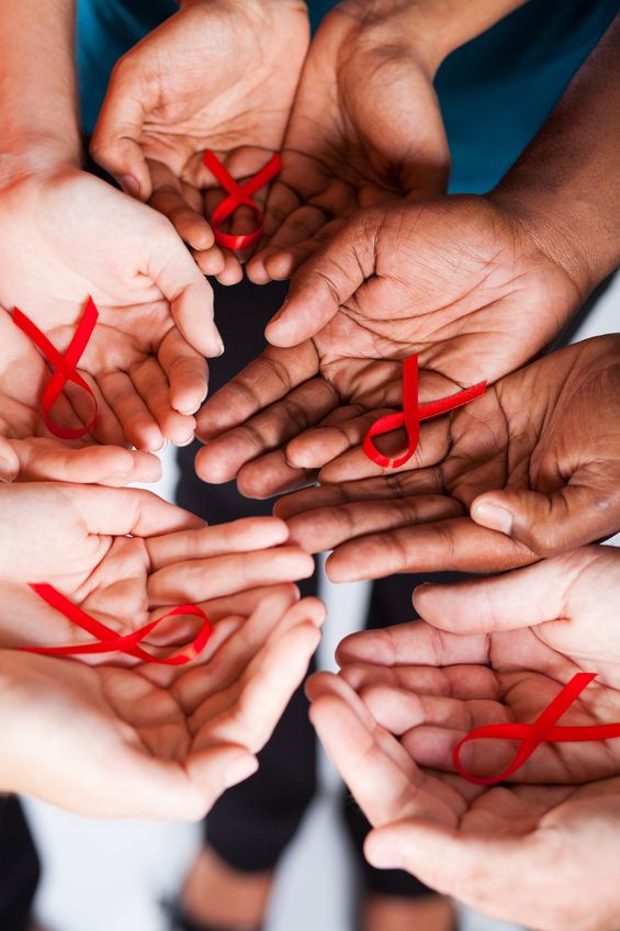 many hands, palms up, with red hope ribbons